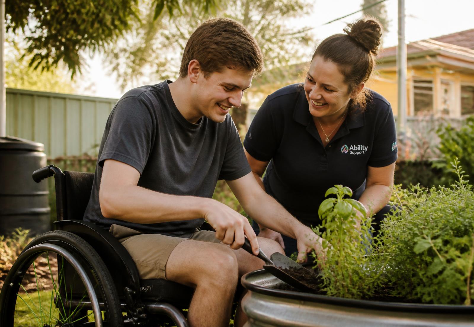A young man using a wheelchair gardening alongside his support worker
